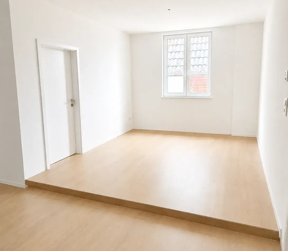 Heller leerer Innenraum mit Holzboden, weißer Tür und Fenster