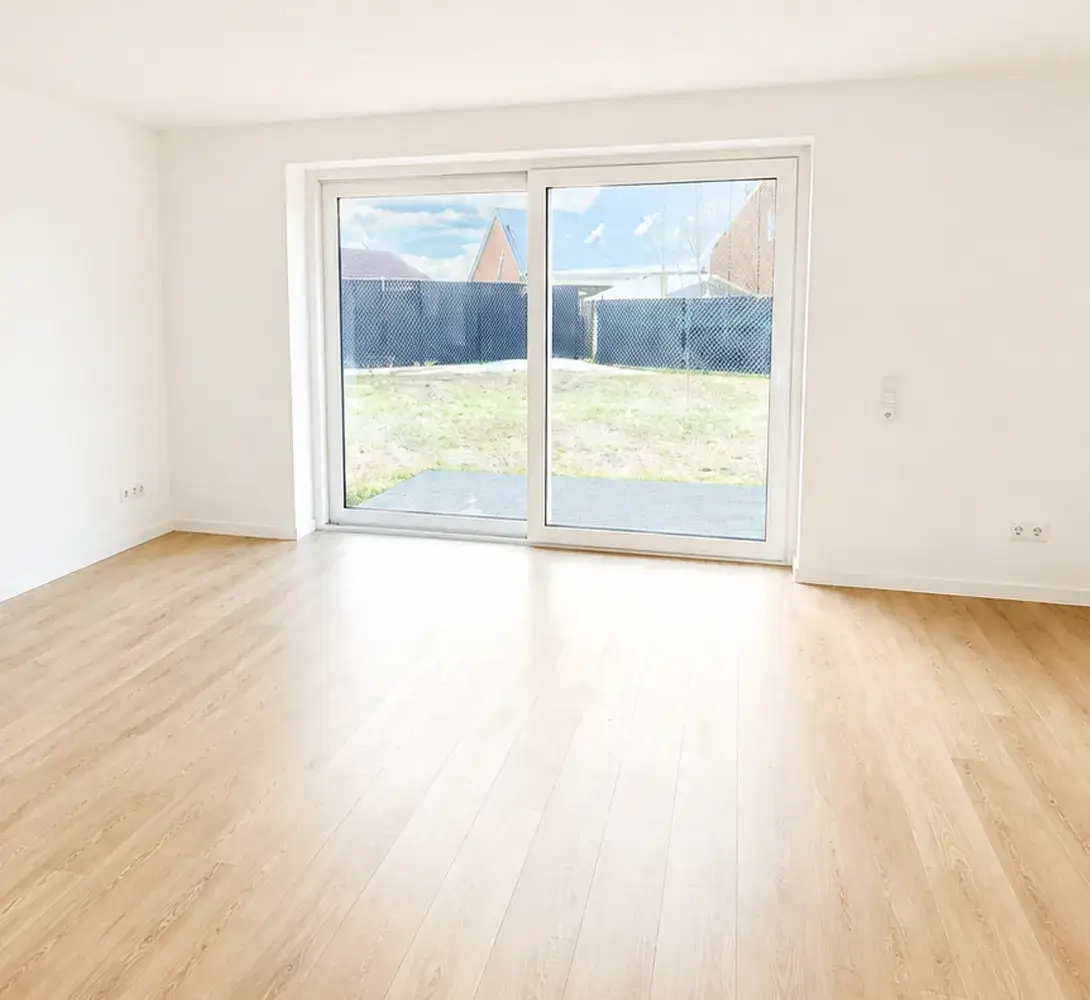 Heller Wohnraum mit Holzboden und großer Terrassentür zum Garten